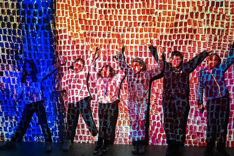 Atelier des lumières - Programme "Art en immersion" - Enfants contre un mur formant une oeuvre d'art